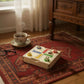 Board game - Ludo set on a vintage rug, featuring colorful buttons and a dice next to a cup of tea.