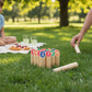 Throwing game - Scatter in a park with players aiming at numbered sticks on the grass for outdoor fun.